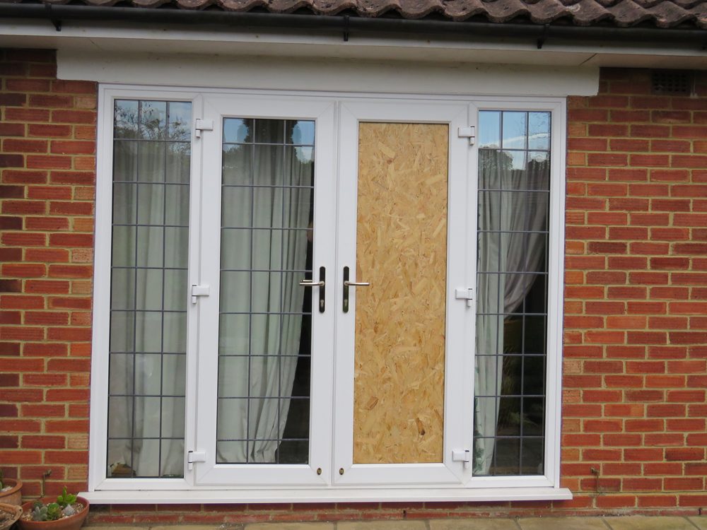 A uPVC French door with one leaf boarded with cut-to-size OSB after a break-in
