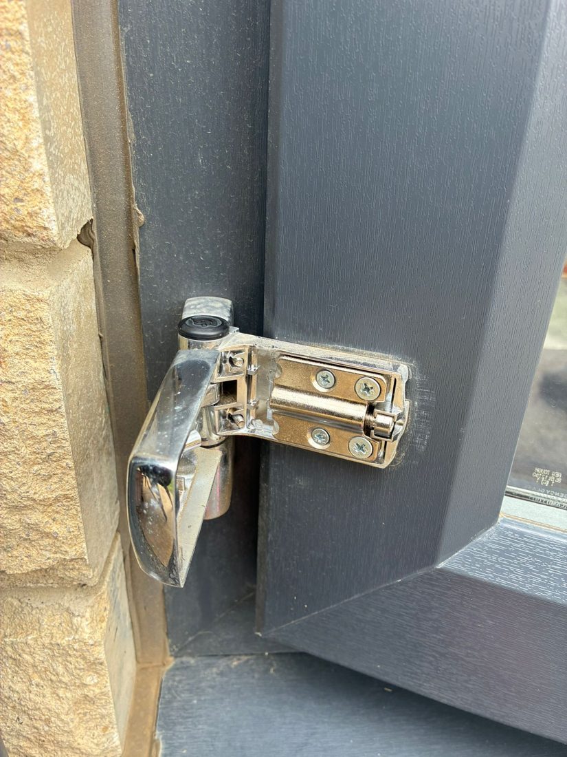 An adjustable flag hinge on a grey composite door being set to correct the door's alignment