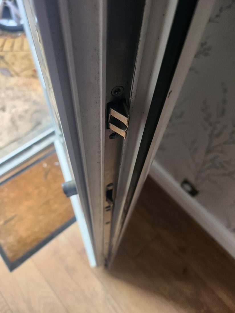 The multipoint hooks and rollers along the edge of an open uPVC door, with the keeps on the frame