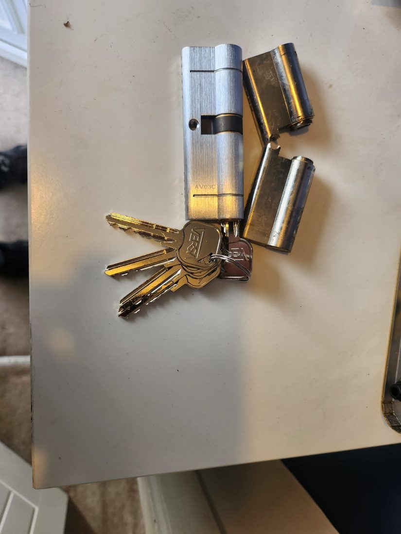 A new euro cylinder with keys beside the old cylinder it replaced, snapped in two
