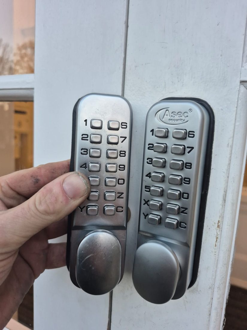 An old code lock held next to its replacement before fitting