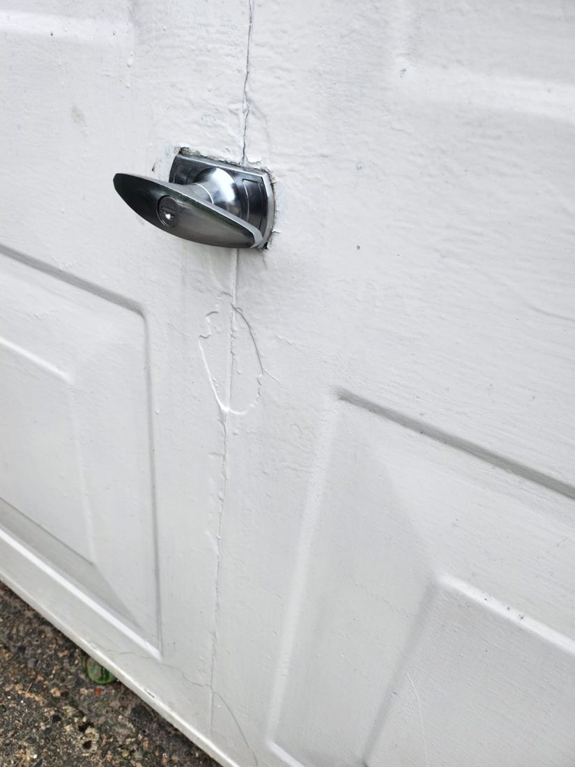 A chrome T-handle newly fitted to a white up-and-over garage door