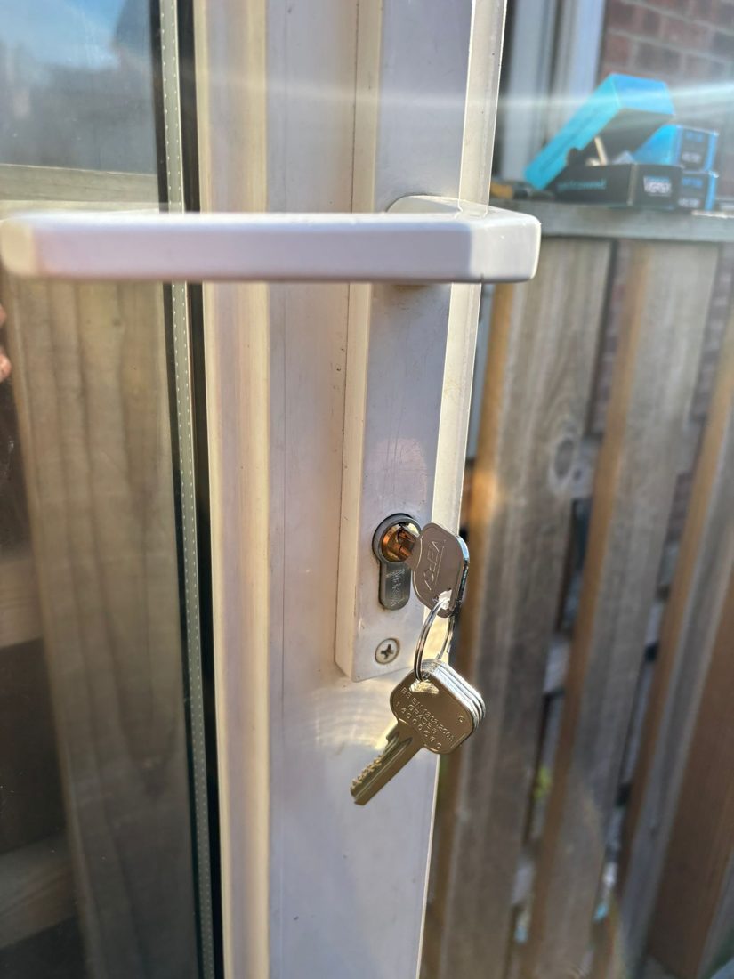 A new euro cylinder and keys fitted to a uPVC door, boxed replacement cylinders on the windowsill behind