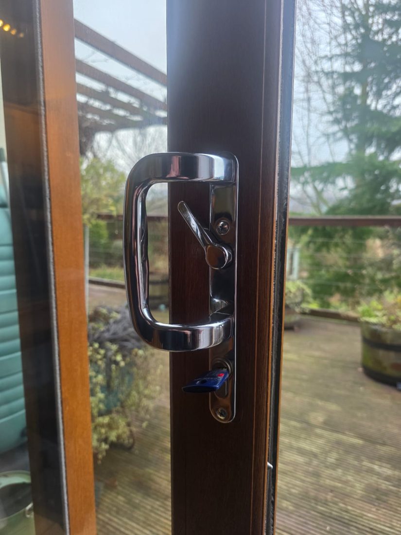 A new chrome handle fitted to a sliding patio door, garden behind