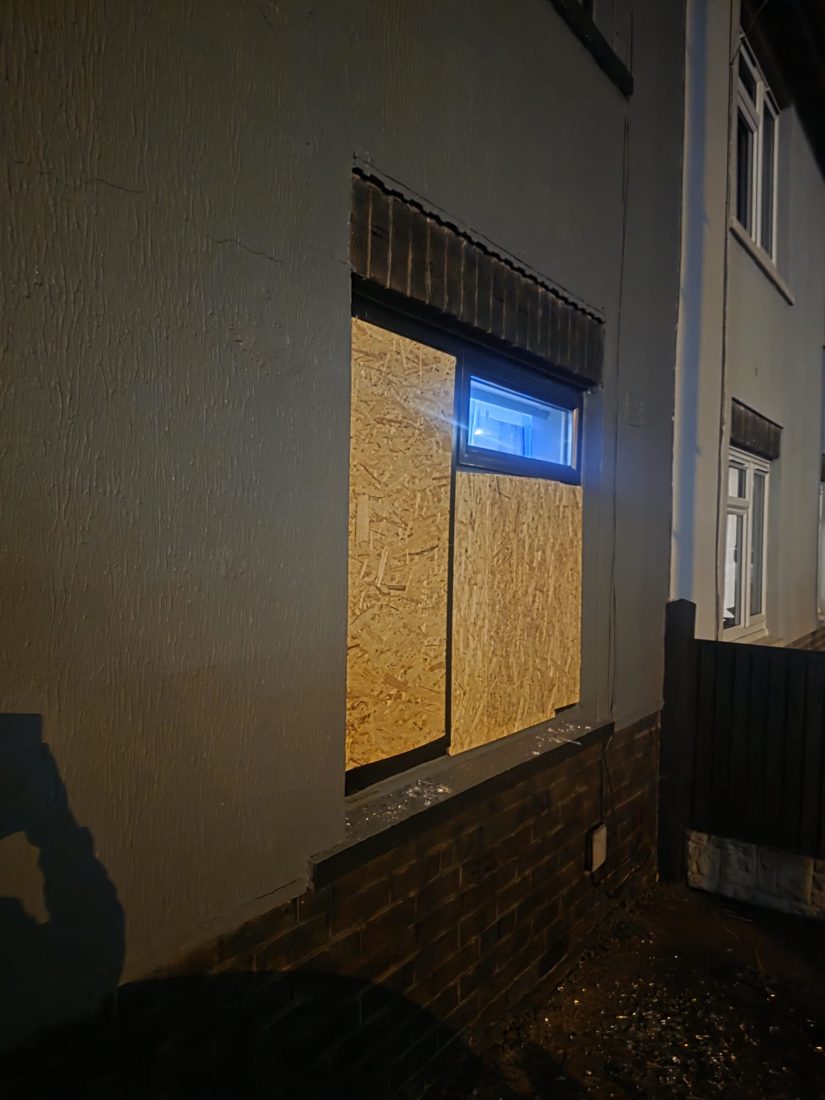 A house window neatly boarded with cut-to-size OSB at night, sealing the opening and making the property secure