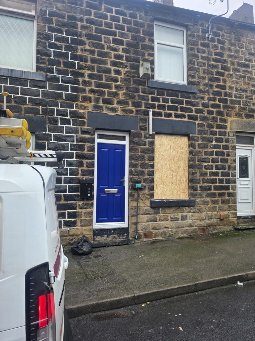 A stone terraced house with a boarded-up front window and the LocksmithLocal van outside after an overnight make-safe