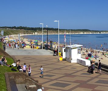 Bridlington's North Beach and promenade on a busy summer's day, with the chalk cliffs of Flamborough Head rising in the distance