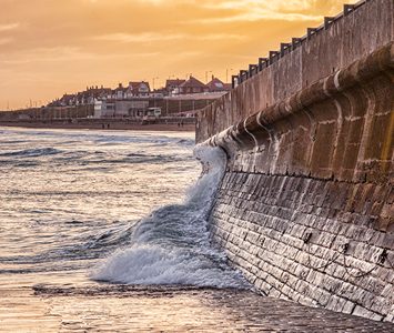 Waves breaking against Bridlington's sea wall at golden hour, the defences that protect the seafront from the North Sea