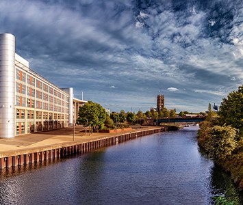 The riverside Waterfront in Doncaster town centre, where Doncaster College's Hub campus stands beside the River Don, with the tower of Doncaster Minster beyond