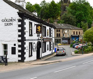 The Golden Lion, a historic black-and-white coaching inn on the main road through Todmorden, with the church tower beyond