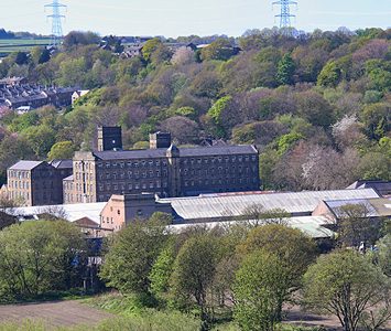 A large former textile mill in its wooded valley setting, a reminder of the milling heritage that shaped the towns and villages around Halifax