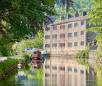 A narrowboat moored on the Rochdale Canal at Hebden Bridge, in the Calder Valley west of Halifax, beside the area's characteristic stacked stone weavers' houses