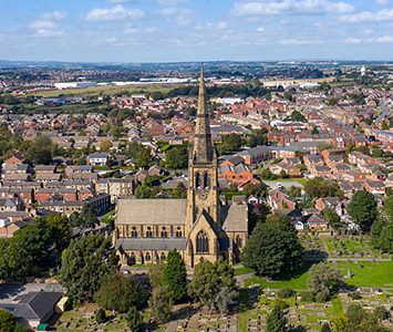 An aerial view over Ossett, the market town's streets gathered around the tall spire of Holy Trinity Church